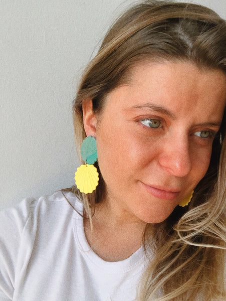 model wearing yellow matte and shimmery teal polymer clay earrings sea shell shape